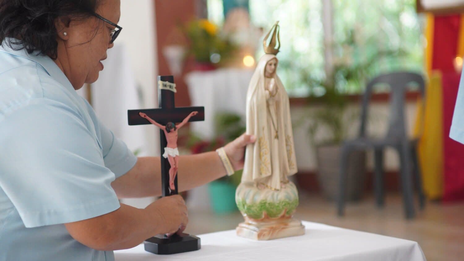 A member of the Community setting a crucifix beside a statue of Our Lady on a table