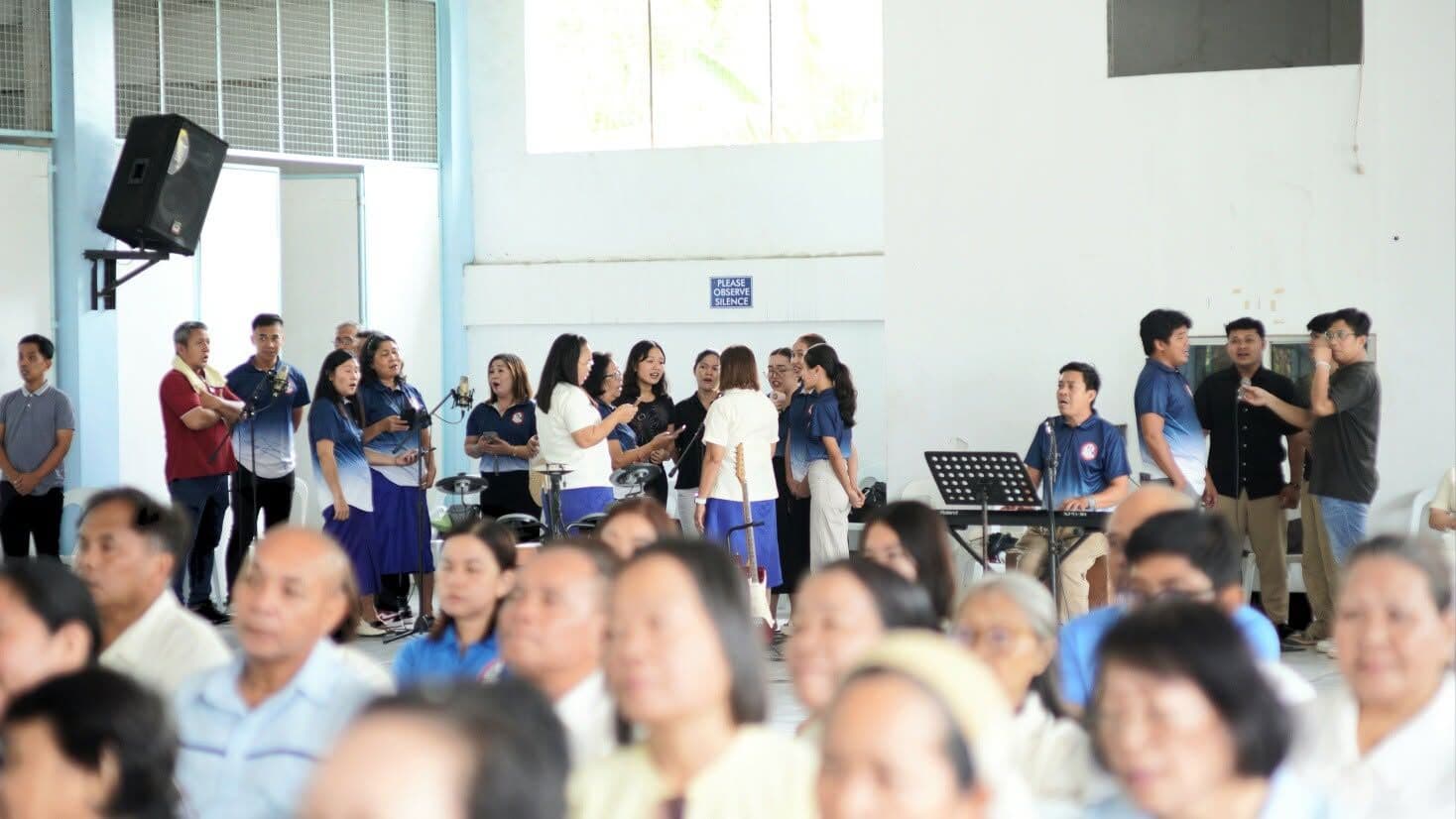 A choir and musicians singing in front of a seated audience