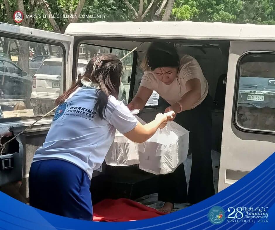 A volunteer in a Working Committee shirt handing out packed meals from the back of a van