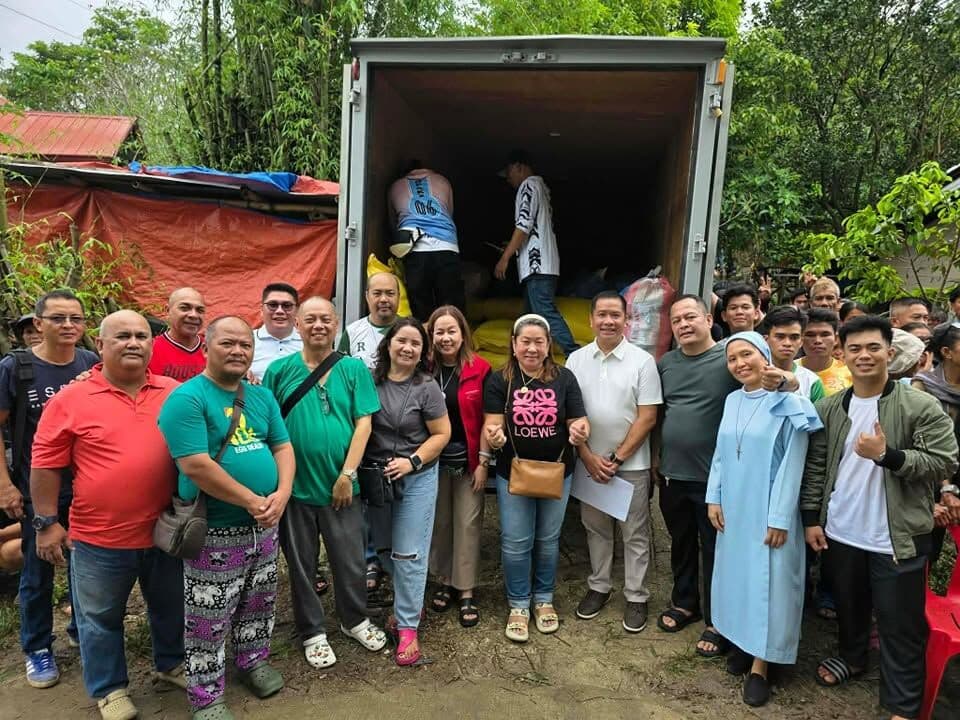 Volunteers and a Sister standing together in front of a truck of relief goods