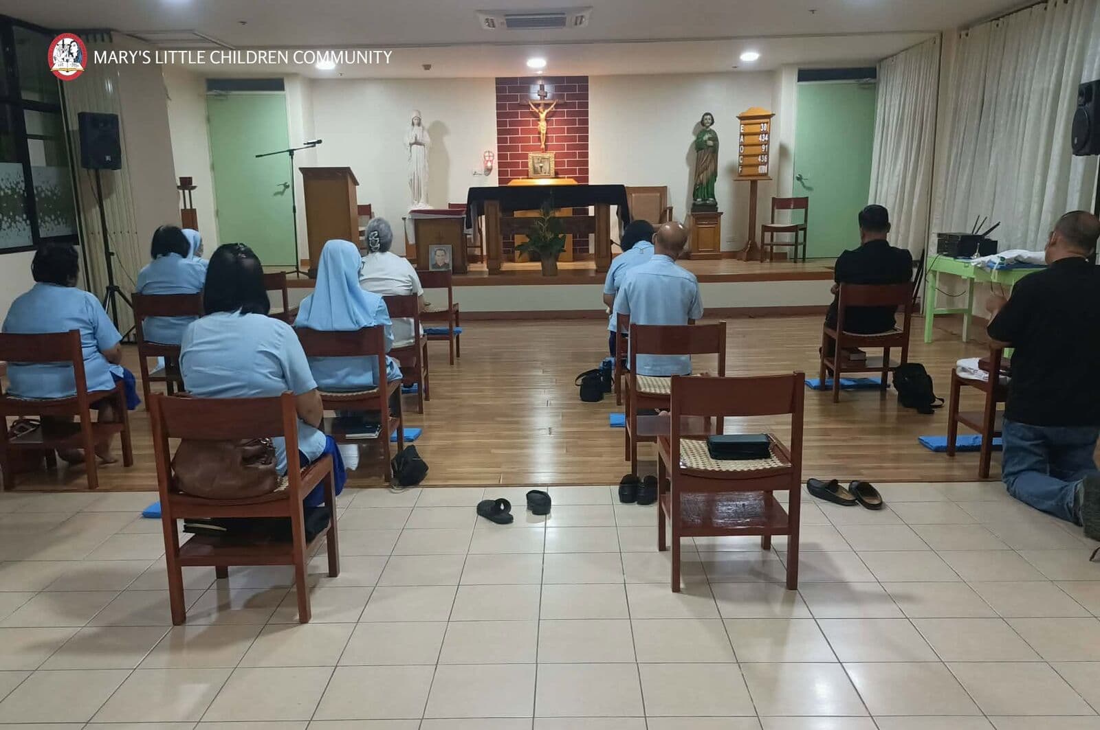 Sisters and members kneeling and sitting in quiet prayer in a small chapel